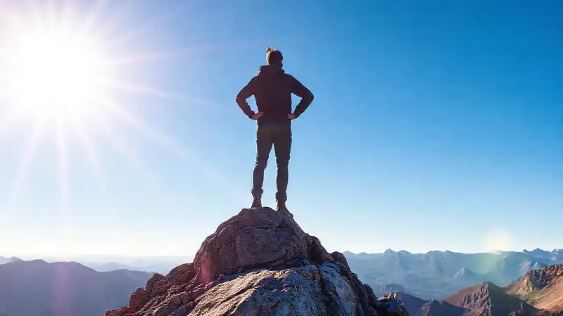 Persona motivada en cumbre, símbolo de logro