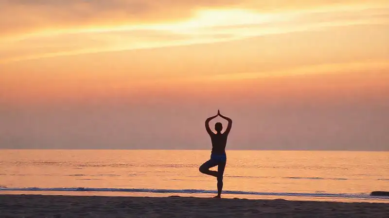 Practica yoga al amanecer en la playa