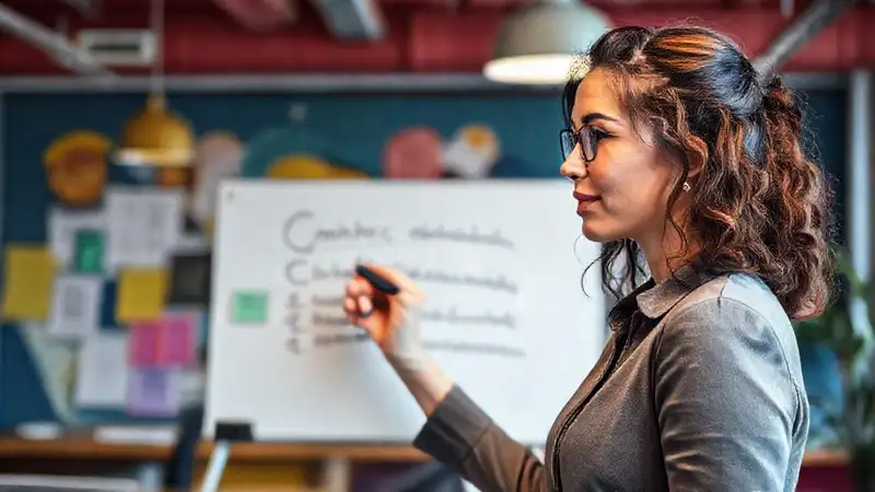 Mujer profesional redacta metas en oficina vibrante