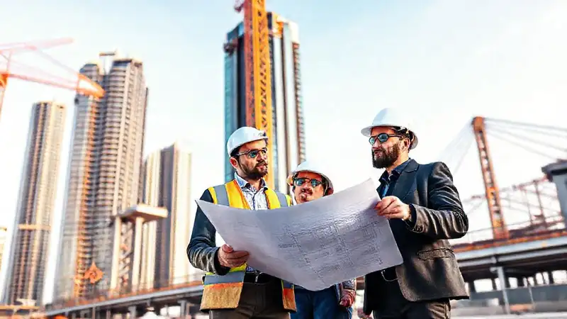 Ingenieros civiles inspeccionan construcción con planos